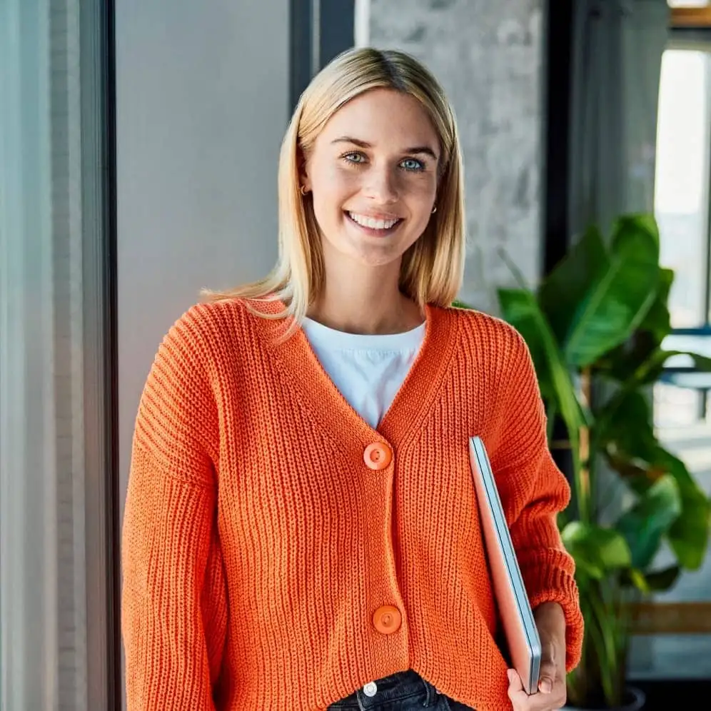 A young businesswoman standing with a laptop in an office.