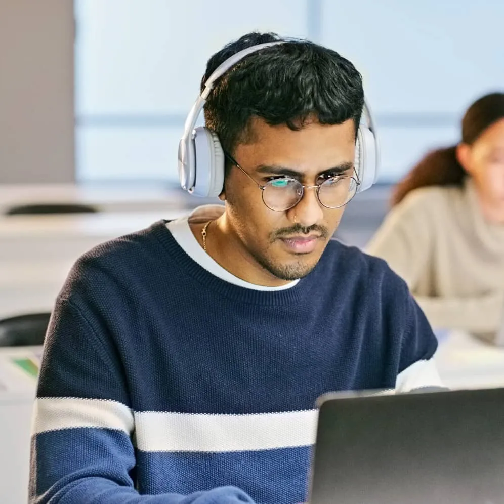 A man wearing headphones, working on a laptop.